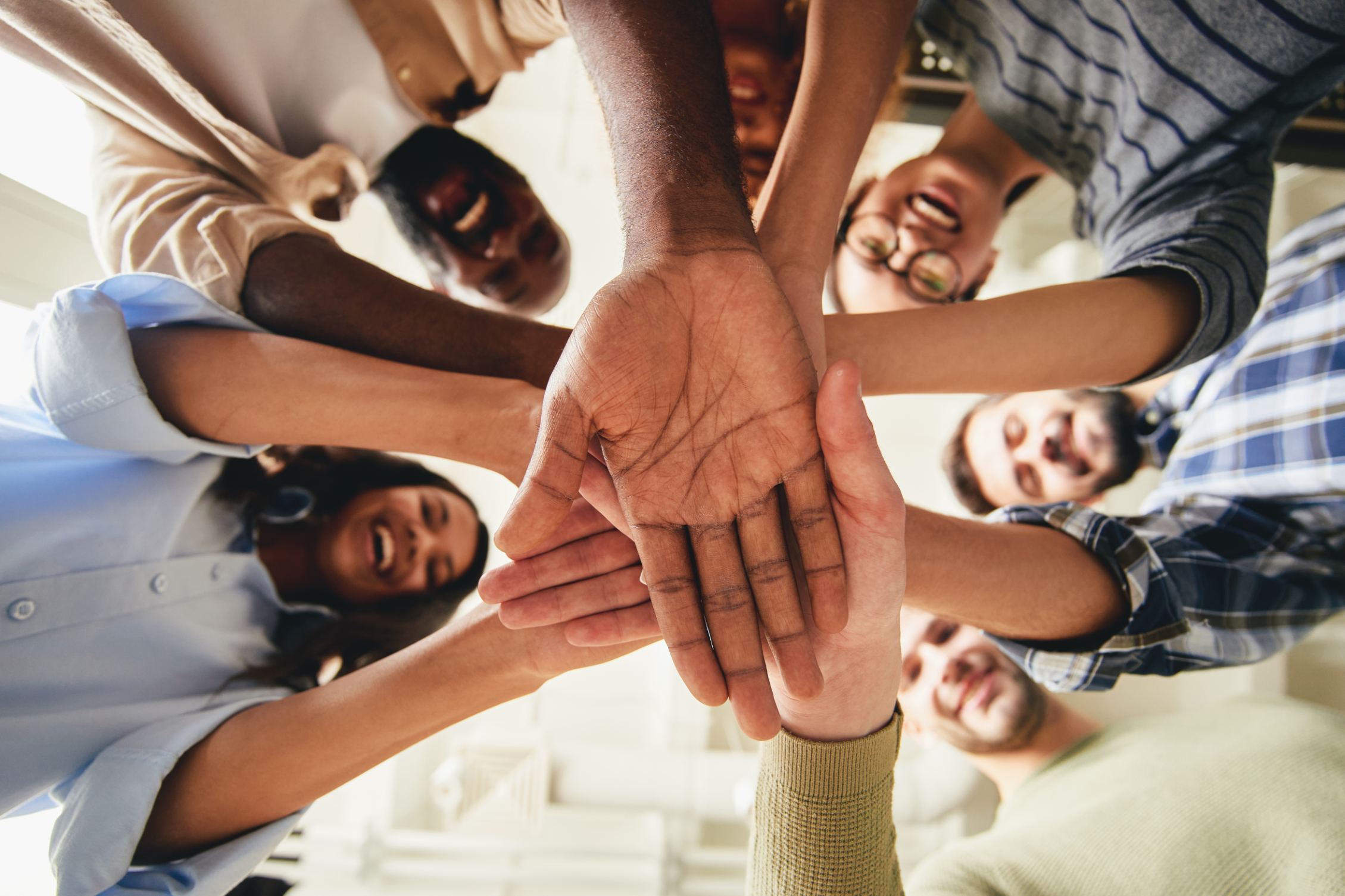 A group of people putting their hands in a circle signifying unity.